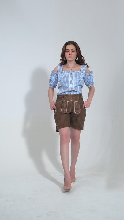 Video showcasing the Elsa Lederhosen for women in Forest Caramel. The video highlights the premium goat suede leather material, intricate natural color embroidery on the bib and legs, two front pockets, a side knife pocket, and the stylish brown horn buttons on the bib and cuffs. The adjustable waistband at the back ensures a snug fit. Note that matching belts and suspenders are not included, allowing for personalized styling.