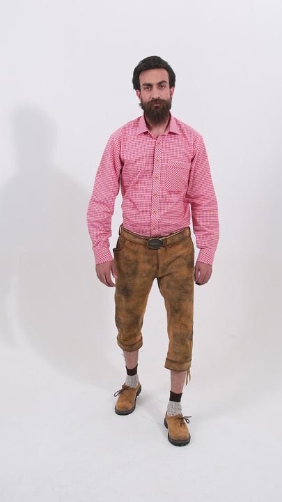 Male model wearing a red checkered shirt and Eltz Bundhosen, featuring intricate embroidery on the front, a decorative belt buckle, and mid-length. The model's hands are by his sides, and he is wearing brown shoes with socks, showcasing the traditional bundhosen in a rotating video to display all angles.